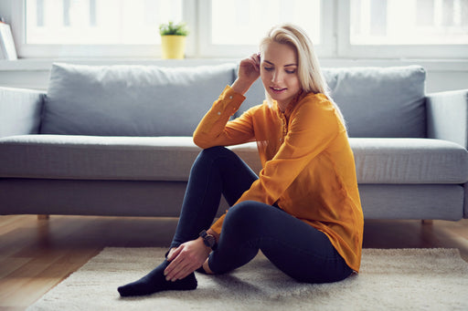 A woman in a yellow jumper, sat on her carpet in her living room that is free from a carpet moth infestation thanks to MothPrevention's products