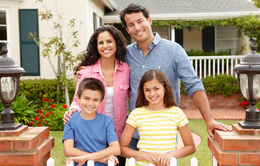a happy family of four standing outside their home that is free from any moth infestations