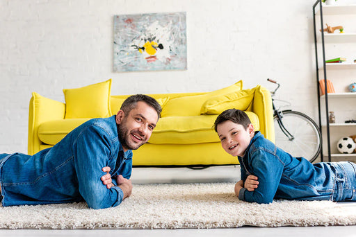 A father and son lying on their carpet that is recently free from a carpet moth infestation.
