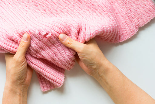 hands holding wool showing moth damage