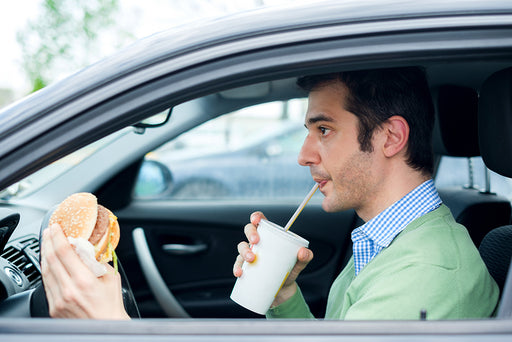 a man drinking and eating in his car