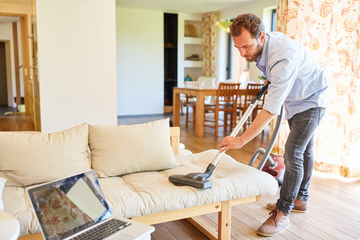 a man vacuuming his couch