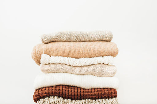 a pile of sweaters in brown and cream colours.