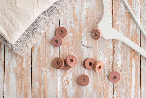 a stack of woollen knitwear next to a hanger and cedar blocks