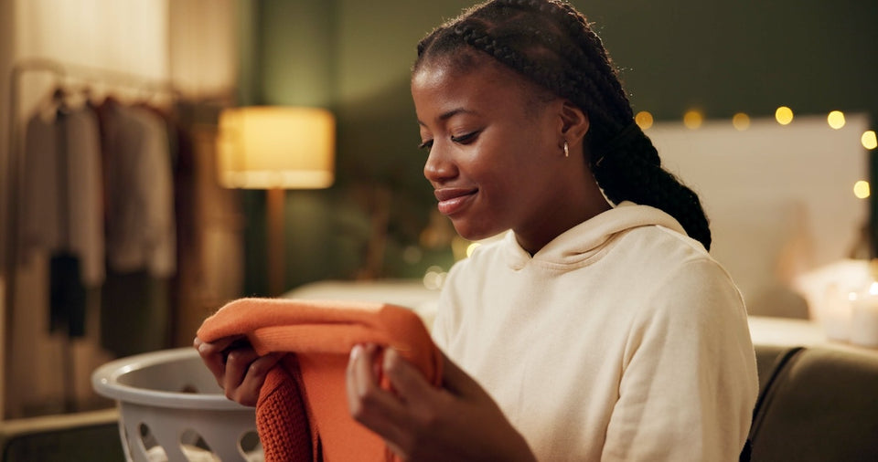 a woman in her bedroom looking at a rust-coloured sweater