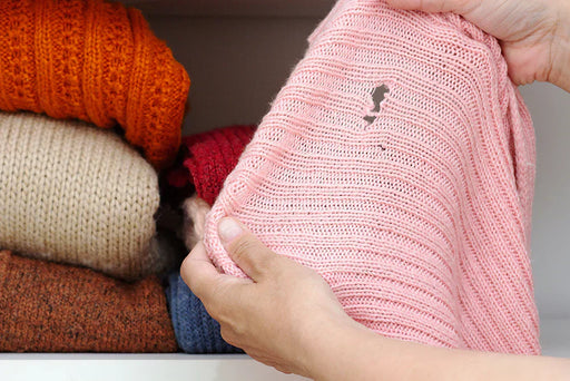 A pink jumper with a big hole in it from a Clothes Moth Infestation