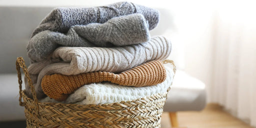 A wicker basket full of a neat pile of knitted jumpers that are free from a clothes moth infestation. 