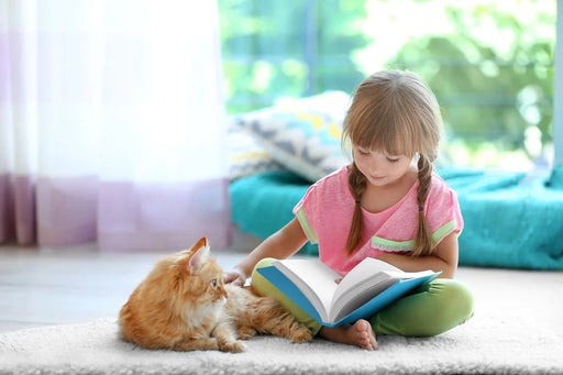 a little girl sitting on a carpet free from a carpet moth infestation, reading her book and stroking her cat