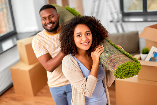  a young couple moving into their new property carrying a roll of carpet