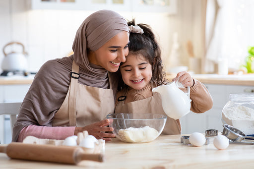 a mother and daughter making a cake in their kitchen