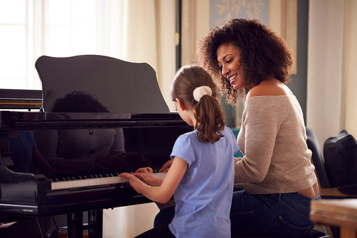 a woman sitting with a young girl at the piano