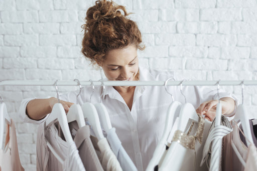 a woman sorting through a clothing rail of garments