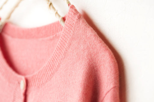a blended wool pink cardigan on a hanger