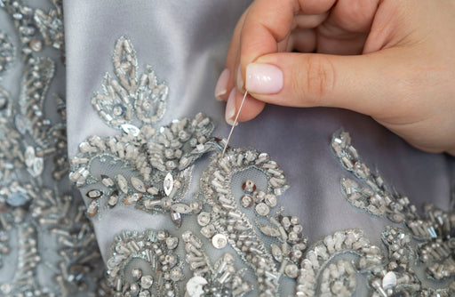 beautiful beading being sewn onto precious grey fabric