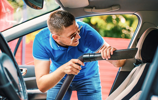 a man cleaning out his car with a vacuum cleaner