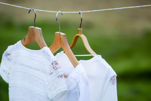 white linen garments on hangers airing outdoors