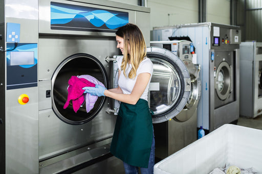 a woman loading a professional dry cleaning machine with clothing