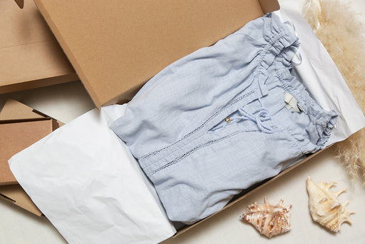 a blue top packaged in a box with tissue paper