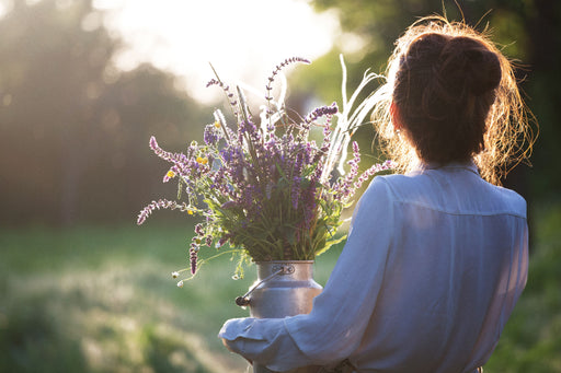 a woman carrying a churn of wild flowers and lavender