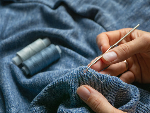 a close up of a fine knit sweater being mended by hand