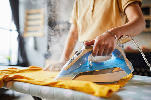 a close up of a steaming iron pressing a piece of clothing