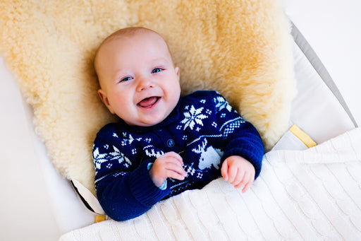 a laughing baby lying on a sheepskin seat liner