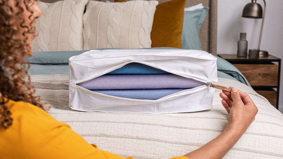 a woman unzipping her breathable cotton storage bag which has sweaters inside