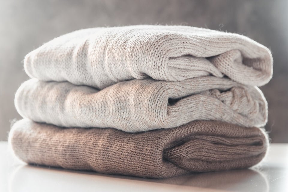 a pile of soft cream and brown cashmere sweaters