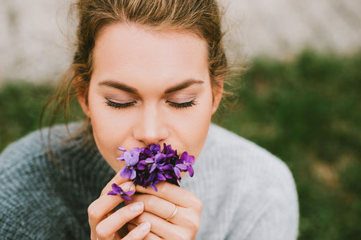 woman in a cashmere sweater smelling flowers