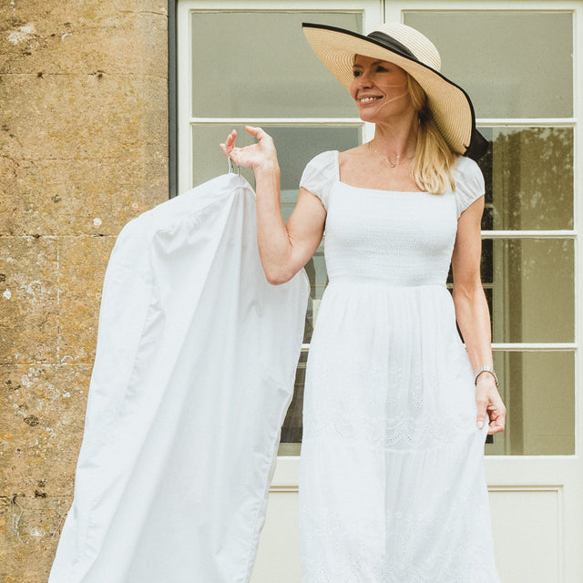 woman in white dress carrying Hayden Hill garment bag