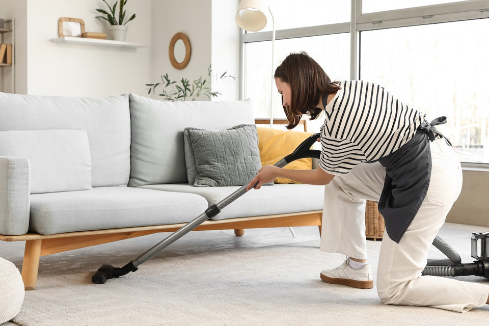 a woman vacuum cleaning under her sofa