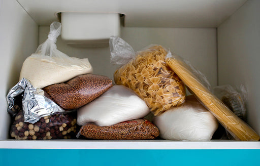 messy bags of pasta, flour, nuts and seeds stored up high in a cupboard