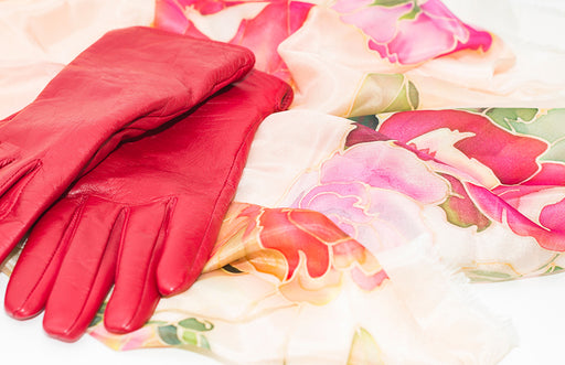 red leather gloves lying on a patterned silk scarf