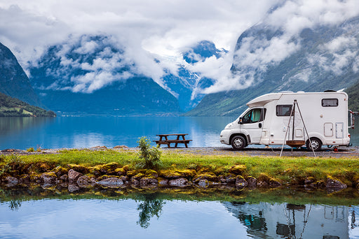 a motorhome parked on the edge of a lake surrounded by mountains