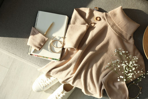 a camel colored cashmere sweater on display with white sneakers