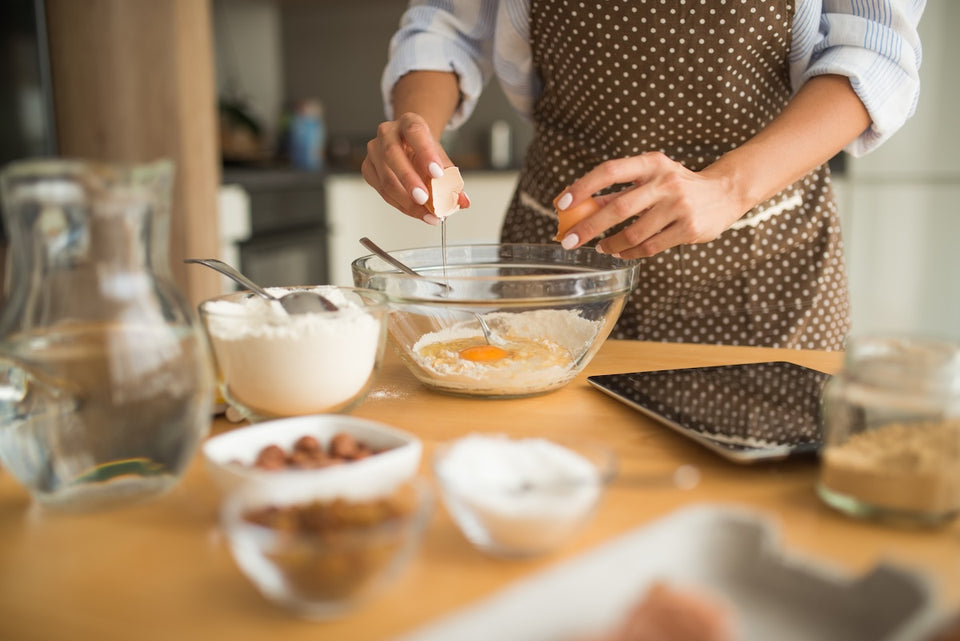a close up of a woman baking with ingredients including flour and nuts on the kitchen table