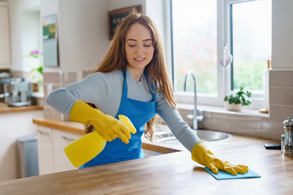 a woman cleaning her kitchen surfaces  with a spray detergent
