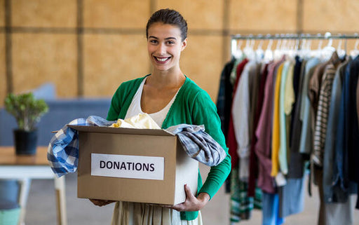 woman holding a donations box full of clothing